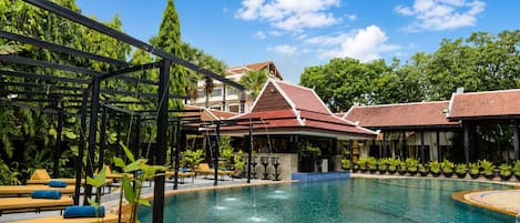 Una piscina al aire libre, sombrillas, sillones reclinables de piscina