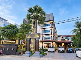 A multi-story hotel with a prominent entrance, palm trees, and a sign indicating 'The Heritage Courtyard'.