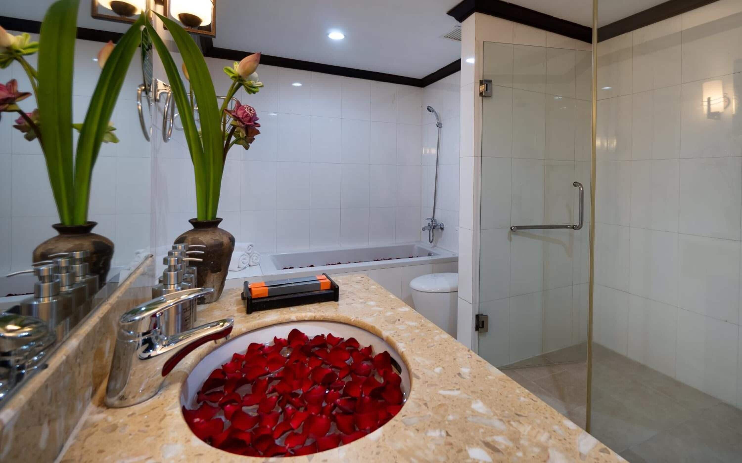 Ein modernes Badezimmer mit Marmorwaschbecken, einer Duschkabine aus Glas und einer Badewanne.