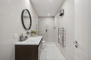 A modern bathroom with a large mirror, a shower, a toilet, and a towel rack. - Middleton Vista - Perfect lake and mountain views. Great for families and groups (Queenstown)