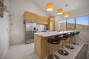 A modern kitchen with a central island, stainless steel appliances, and a large window offering a desert view. - Middleton Vista - Perfect lake and mountain views. Great for families and groups (Queenstown)