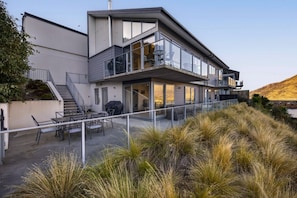 A modern two-story house with a balcony, outdoor seating, and a view of the surrounding landscape. - Middleton Vista - Perfect lake and mountain views. Great for families and groups (Queenstown)