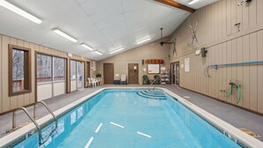 Una piscina interior con ventilador de techo, calentador de agua y escalera de piscina.