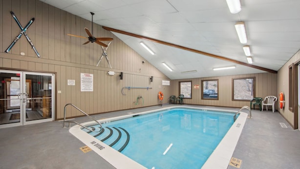 Una piscina sin letreros de prohibido bucear, un ventilador de techo y un cartel de salvavidas en la pared.