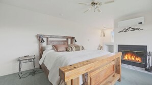 Ein Schlafzimmer mit einem Bett, einer hölzernen Bank, einem Kamin und einem Deckenventilator.