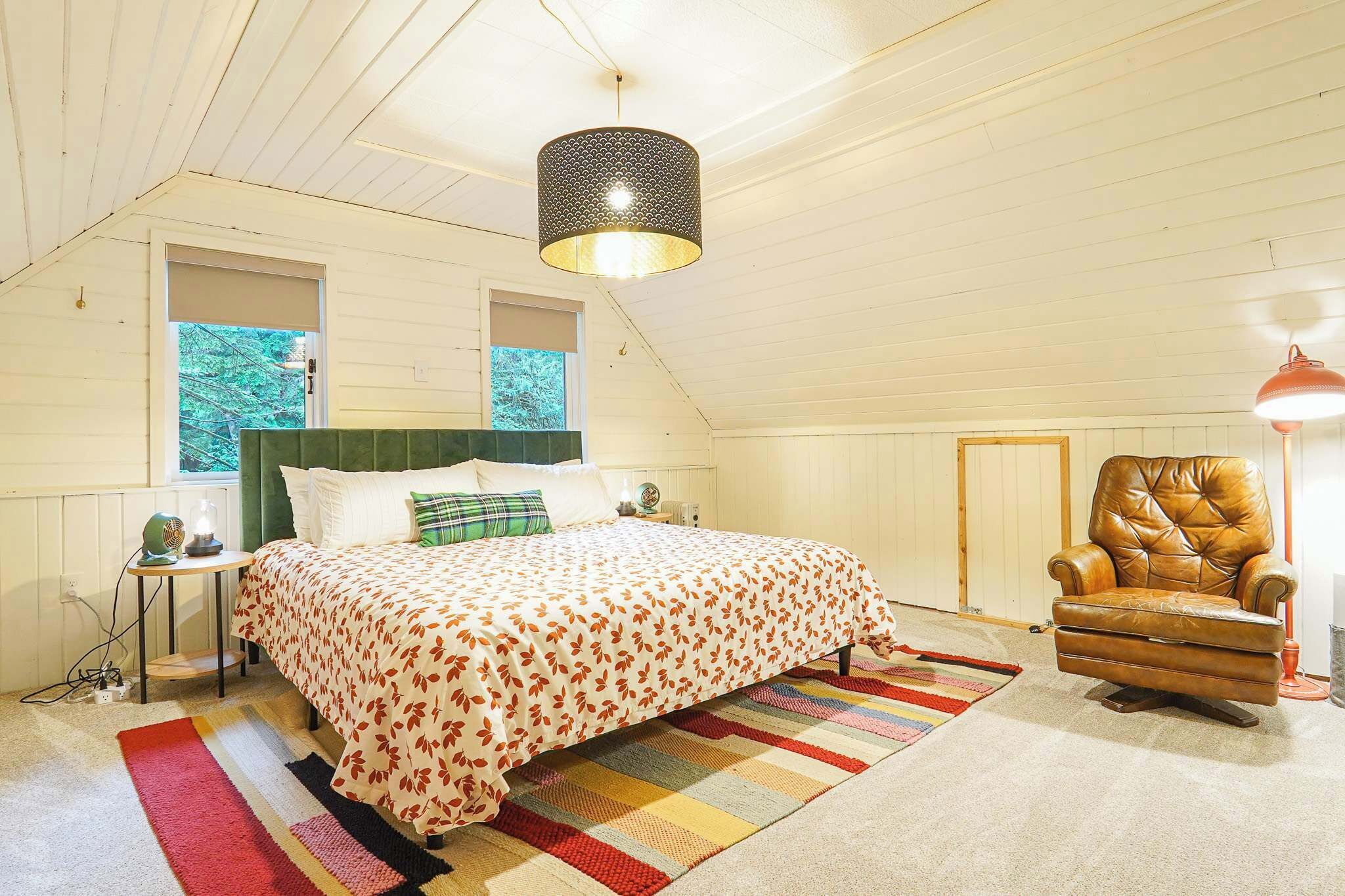 A bedroom with a bed, a chair, a lamp, and a window.