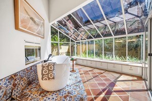 A conservatory with a glass ceiling, a patterned bench, and a view of greenery outside. - Carmel Valley Sun Lodge | Private and Spacious (Carmel Valley)