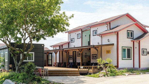 Een gebouw met twee verdiepingen, een overdekte veranda, zitplaatsen buiten en een bord waarop een restaurant aangegeven staat.