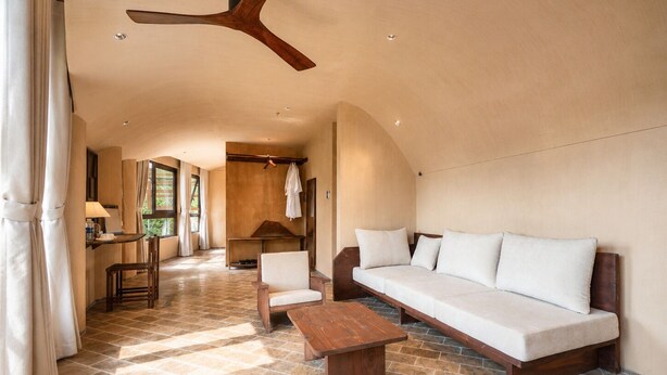 A spacious living area with a wooden ceiling fan, a sofa, a wooden coffee table, and a dining table with chairs. - Cam Ly The Boutique (Cam Ly - Da Lat)