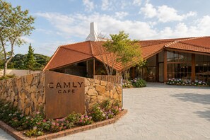 A stone wall with 'CAMILY CAFE' signage, a tiled roof, and a paved entrance area with flowers. - Cam Ly The Boutique (Da Lat)