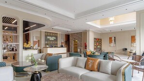 A hotel lobby with a reception desk, seating areas, and a bar. - Solaya hotel (Van Don)