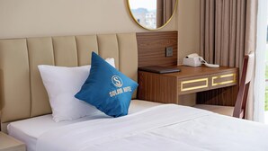 A hotel room with a bed, a nightstand with a phone, a blue pillow, and a mirror on the wall. - Solaya hotel (Van Don)