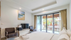 Una camera d'albergo con un letto, una scrivania con televisore, una sedia e un balcone con vista.