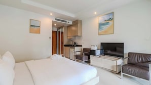 Camera d'albergo con un letto, una TV, una scrivania e angolo cottura.