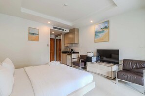 Una habitación de hotel con una cama, televisión, escritorio y kitchenette.