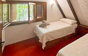 Ein kleines Zimmer mit einem Einzelbett, einem Fenster, einem Nachttisch und einem roten Teppich.
