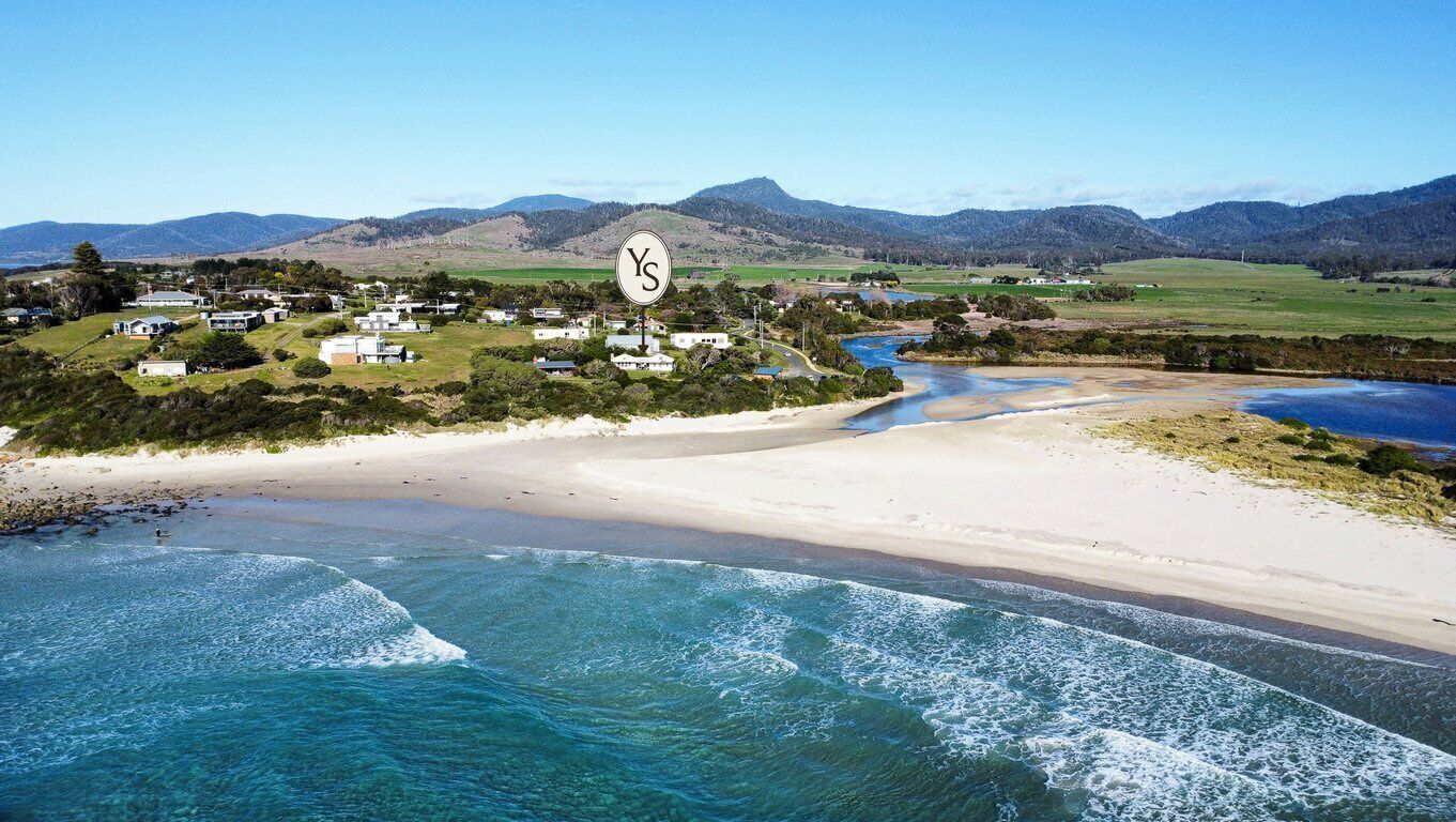 Zona costera con playa, río y un poblado con casas.
