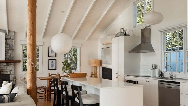 Een moderne keuken met een centraal eiland, witte kasten en een stenen open haard.