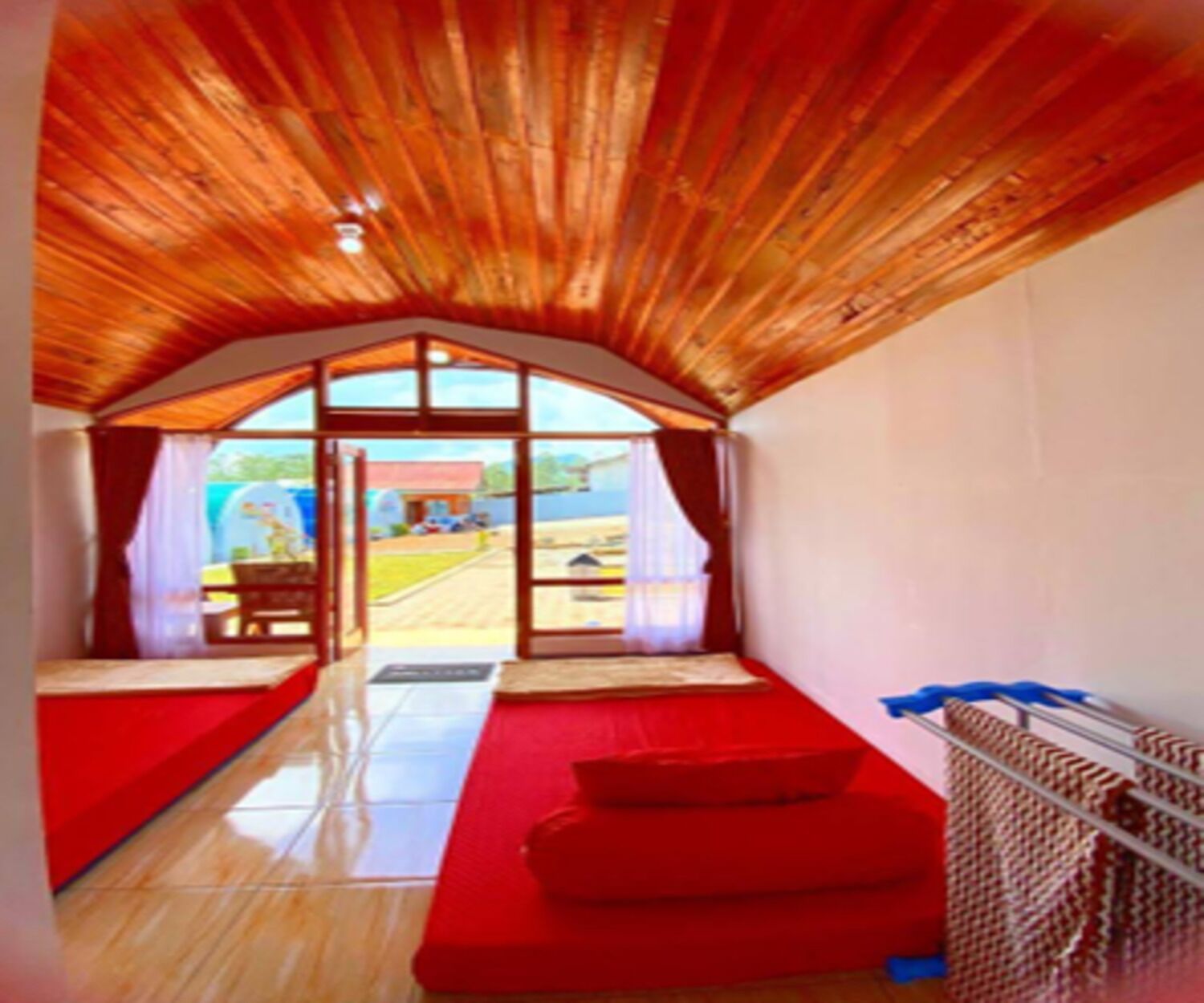 A room with a sloped ceiling, a red sofa, a small table, and a view through a large window.