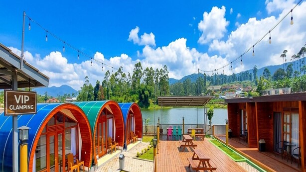 Uma área de glamping com tendas coloridas, um deck de madeira e vista para o lago.