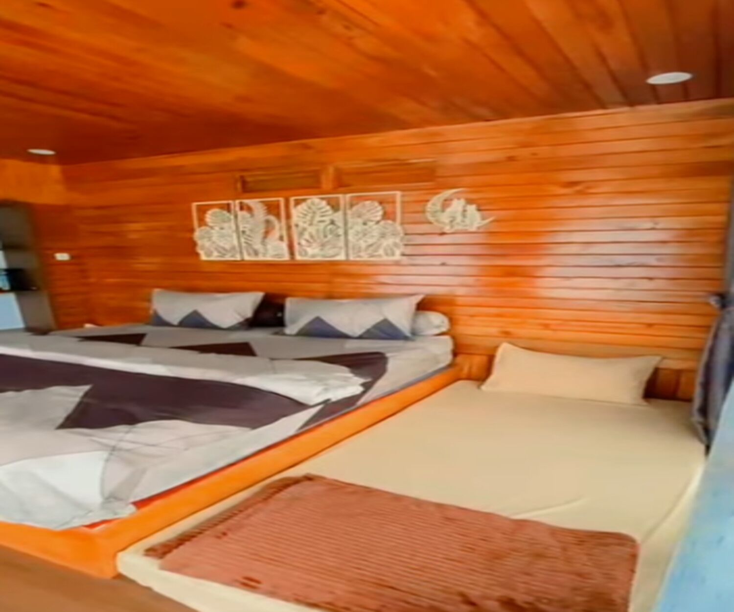 A wooden cabin-style room with a bed, pillows, and a wall-mounted artwork.