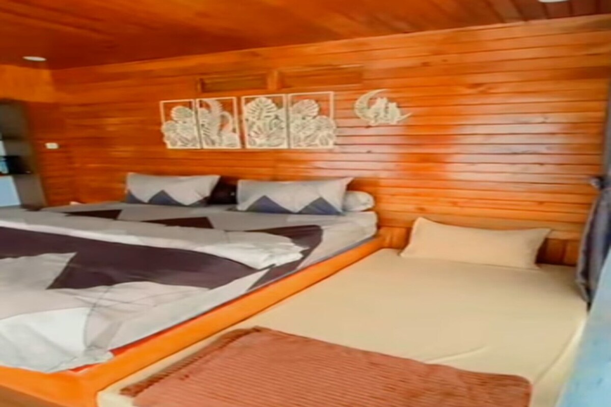 Ein holzgetäfeltes Zimmer im Chalet-Stil mit einem Bett, Kissen und einem Wandbild.