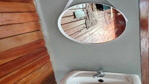 Um banheiro com piso de madeira, pia branca e espelho.