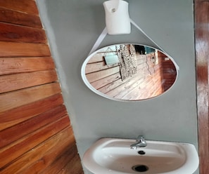 A bathroom with a wooden floor, a white sink, and a mirror. - Cozzy Rompok Cileunca (bandung)