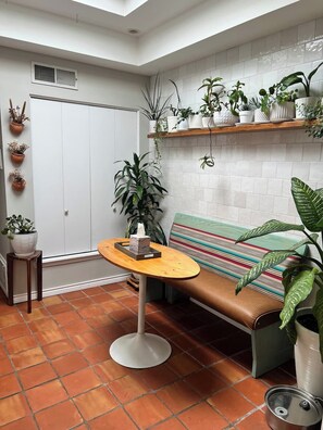 A cozy room with a bench, a round table, and various potted plants. - Las Cruces Landing Pad - Available July to November (Mesilla)