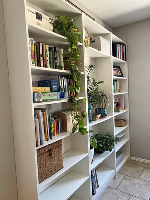 A bookshelf with books, a plant, and a basket. - Las Cruces Landing Pad - Available July to November (Mesilla)