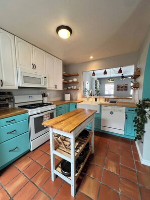 A kitchen with white cabinets, a wooden countertop, a stove, a microwave, a dishwasher, and a tiled floor. - Las Cruces Landing Pad - Available July to November (Mesilla)