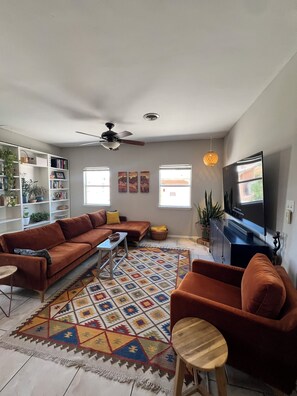 A living room with a sofa, armchair, TV, bookshelf, and decorative rug. - Las Cruces Landing Pad - Available July to November (Mesilla)