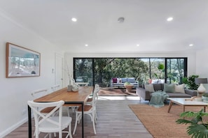 Ein modernes Interieur mit Essbereich, Sofa und großen Fenstern.