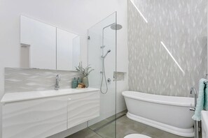 Ein modernes Badezimmer mit Duschabtrennung aus Glas, einer freistehenden Badewanne und einem Waschtisch mit Marmorplatte.