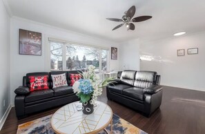 Ein Wohnzimmer mit zwei schwarzen Ledersofas, einem Couchtisch und einem Deckenventilator.