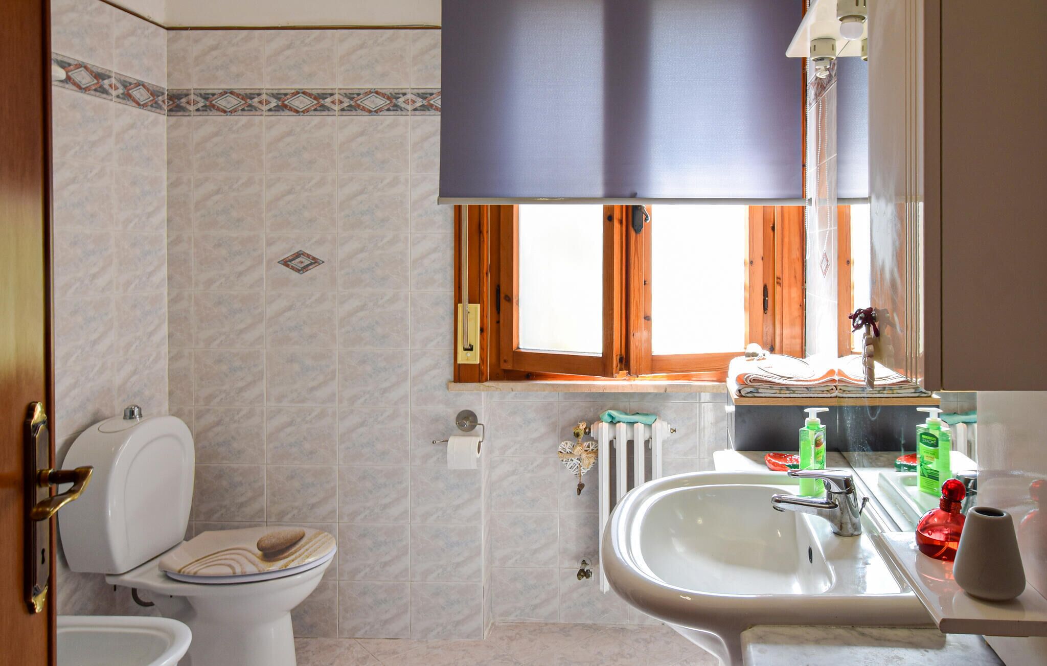 Een badkamer met toilet, wastafel en raam.