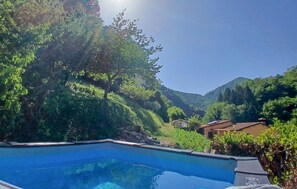 Une piscine offrant une vue sur un paysage montagneux, avec un petit bâtiment en arrière-plan.
