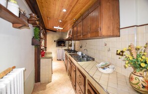 Eine schmale Küche mit Holzschränken, einer Fliesenküche und einem eingebauten Backofen.