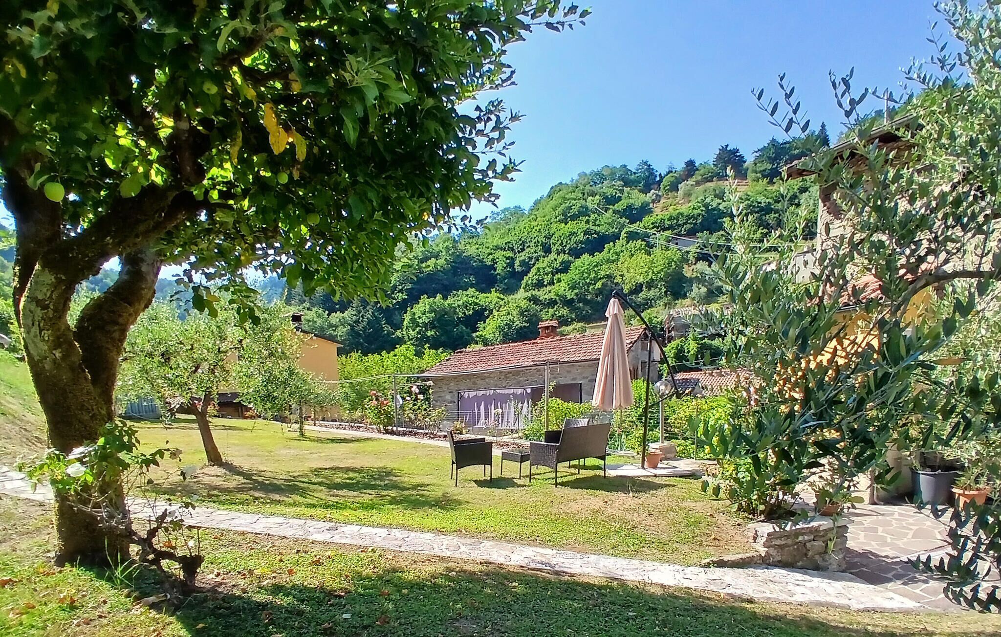 A garden with outdoor seating, a stone pathway, and a building with a tiled roof.