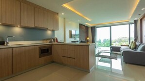 A modern kitchen with wooden cabinets, a central island, and a dining area with a sofa. - Sea View the tree 1BR Condo 500m Walk 2 BeachC260 (Tambon Rawai)