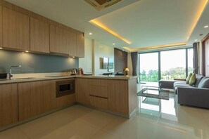 A modern kitchen with wooden cabinets, a central island, and a dining area with a sofa. - Sea View the tree 1BR Condo 500m Walk 2 BeachC260 (Tambon Rawai)