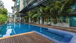A modern hotel with a swimming pool, wooden deck, and tropical plants. - Sea View the tree 1BR Condo 500m Walk 2 BeachC260 (Tambon Rawai)