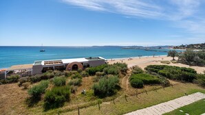 Blick auf die Küste mit Strand, einem Gebäude mit flachem Dach und blauem Himmel.