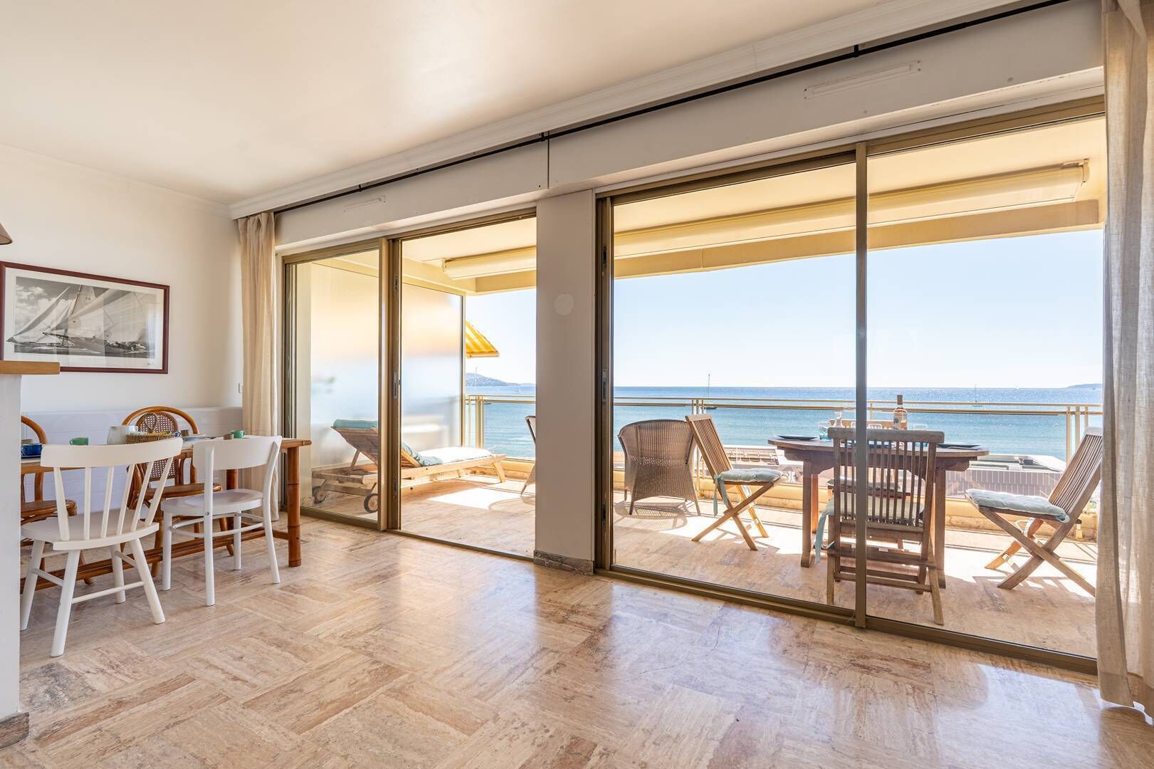 Ein Zimmer mit einer Schiebeglastür, die auf einen Balkon mit Meerblick führt.