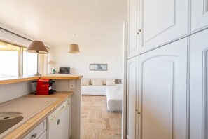 Eine moderne Küche mit einer Holz Arbeitsplatte, einem roten Gerät und einem Essbereich mit einem weißen Sofa.