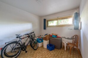 Ein kleiner, kompakter Raum mit einem Fahrrad, einem Stuhl, einem Fenster und einer Werkbank.