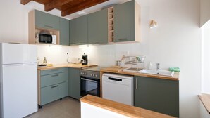 A compact kitchen with a microwave, oven, dishwasher, and wooden countertop.
