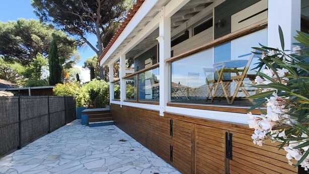 Une maison moderne dotée d’une terrasse en pierre, d’un revêtement extérieur en bois et de grandes fenêtres.