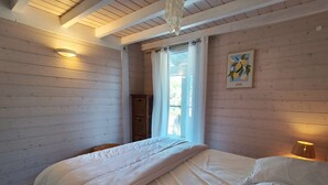 Une chambre à coucher avec un lit, des murs en bois, une fenêtre avec des rideaux et une lampe fixée au mur.