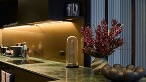 A modern kitchen with a built-in stove, a glass-enclosed coffee machine, and a decorative vase with flowers. - The Grand Heritage Suite · 4 Bed · Entire Floor (Auckland City)